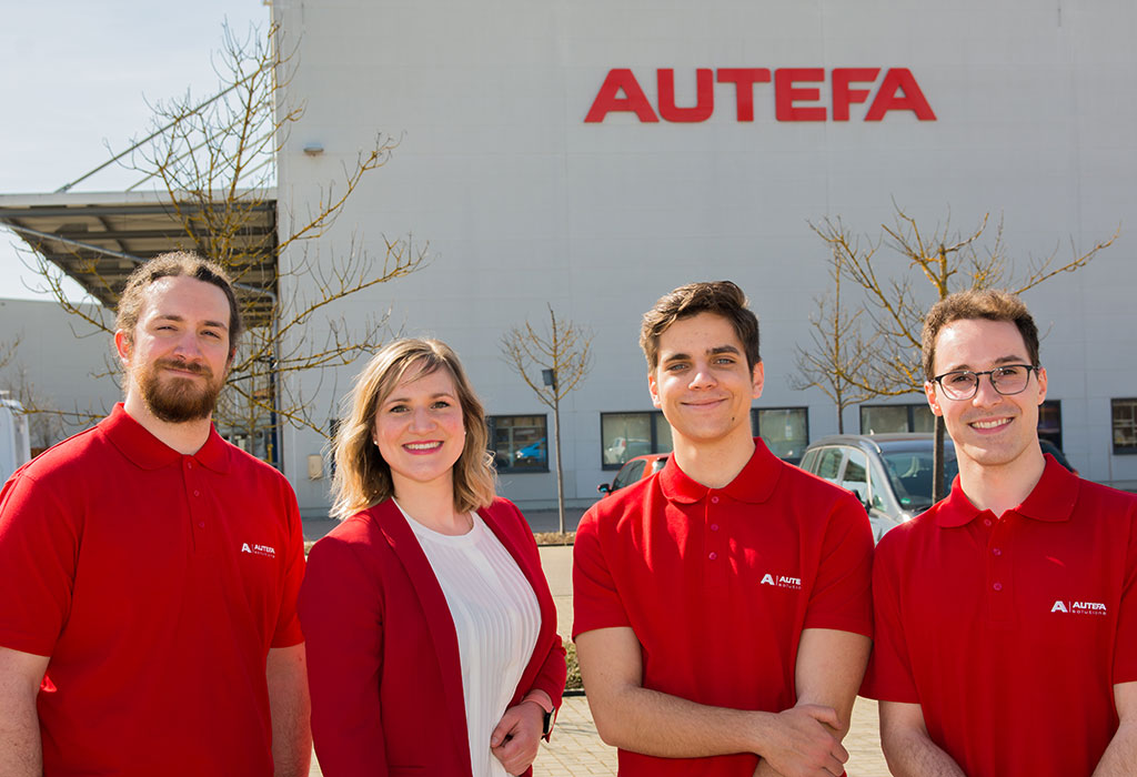 Four university students in red clothes in front of the company building