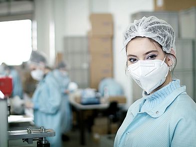 Pretty worker with protective clothing and face mask smiling