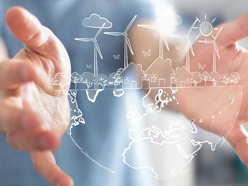 Hands hold image of a globe with houses, trees and windmills