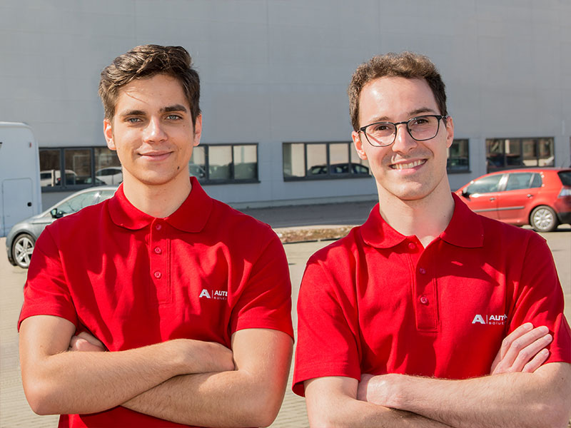 Two university students in red clothes in front of the company building